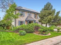 Charming two-story brick home with blue shutters and a lush, well-maintained front yard with mature trees at 12610 E Villanova Dr, Aurora, CO 80014