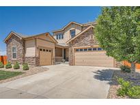 Charming two-story home with a stone and siding exterior, driveway, mature tree and multiple garage doors at 5923 S Jamestown Ct, Aurora, CO 80016
