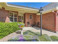 Inviting brick home entrance with colorful flowers and a seating area, creating a warm welcome at 2700 W Riverwalk Cir # C, Littleton, CO 80123