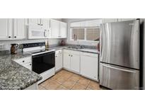 Bright kitchen features granite countertops, stainless steel refrigerator, and white cabinetry at 5095 S Newcombe Ct, Littleton, CO 80127