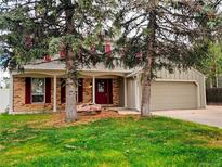Charming two-story home with a brick facade, red shutters, and a well-manicured lawn and mature trees at 11427 Brownstone Dr, Parker, CO 80138