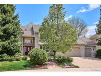 Charming two-story home featuring a stone facade, red front door, and mature landscaping at 5320 S Geneva St, Englewood, CO 80111
