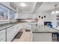 Bright kitchen features white cabinetry, granite countertops, stainless steel sink, and modern appliances at 1294 S Troy St, Aurora, CO 80012