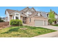 Charming two-story home featuring a brick facade, a well-manicured lawn, and a spacious two car garage at 8958 Forrest Dr, Highlands Ranch, CO 80126