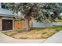 Townhome exterior with brick garage, wood fence and mature shade tree on a grassy lot at 9967 Lane St, Thornton, CO 80260
