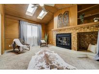Charming living room featuring a wood-paneled vaulted ceiling with skylights and a cozy brick fireplace at 9967 Lane St, Thornton, CO 80260