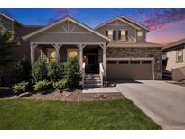 Charming two-story home featuring stone accents, a covered porch, and a well-maintained lawn at sunset at 6193 Saddle Bow Ave, Parker, CO 80134