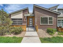 Charming brick home features a modern door, stylish landscaping, and unique architectural details at 12441 W Virginia Ave, Lakewood, CO 80228