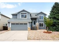Charming two-story home boasts a well-manicured lawn, inviting entrance, and attached two-car garage at 8879 Apache Plume Dr, Parker, CO 80134
