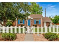 Charming brick home features a well-manicured lawn and delightful white picket fence, and eye-catching blue shutters and front door at 1691 Roslyn St, Denver, CO 80220