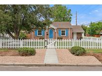 Charming brick home with bright blue door, shutters and white picket fence at 1691 Roslyn St, Denver, CO 80220