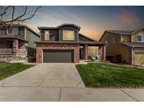 Charming two-story home featuring a brick facade, well-manicured lawn, and a two-car garage at 5079 Morning Glory Pl, Highlands Ranch, CO 80130