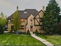 Charming brick home with a well-manicured lawn, mature trees, and an inviting walkway leading to the front door at 3811 E 26Th Avenue Pkwy, Denver, CO 80205