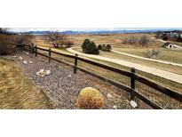 Rustic yard with a wooden fence, walking path, and distant mountain views creates a serene natural retreat at 227 Powderhorn Trl, Broomfield, CO 80020