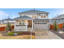 Charming two-story home with a covered front porch, stone accents, a two car garage, and a well manicured yard at 7547 S Patsburg Way, Aurora, CO 80016