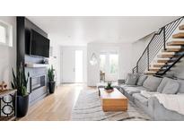 Bright living room features a fireplace, flatscreen television, and modern staircase to the second level at 2685 S Acoma St, Denver, CO 80223