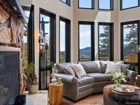 Inviting living room with stone fireplace and large windows offering mountain views at 1194 Snyder Mountain Rd, Evergreen, CO 80439