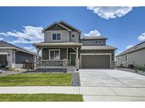 Charming two-story home featuring a covered porch, stone accents, and a well-manicured lawn at 13708 Daffodil Pt, Parker, CO 80134