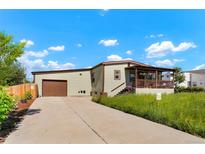 Ranch-style home with attached garage and covered porch at 6653 N Knox Ct, Denver, CO 80221