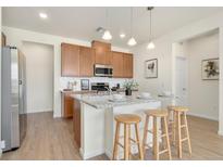 Bright kitchen features wood cabinets, stainless steel appliances, granite counters and pendant lighting at 6153 N Ceylon St # 203, Denver, CO 80249