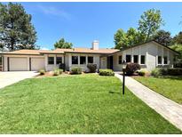 Charming ranch style home with beautiful lawn, landscaped yard, and attached two car garage at 9451 E Evans Pl, Denver, CO 80231
