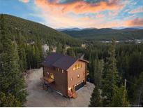 Stunning exterior of the mountain home nestled in a forest with a charming deck and welcoming front porch at 57 Overlook Ct, Idaho Springs, CO 80452