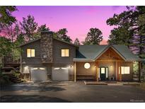 Charming two-story home features a stone chimney, a front porch with a wooden structure, and a well-maintained yard at 26196 Rea Ave, Conifer, CO 80433