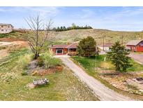Charming ranch-style home with a long driveway and well-maintained lawn and mature trees at 12101 Riverdale Rd, Brighton, CO 80602