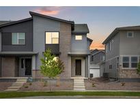 Modern townhome featuring a stylish gray facade with brick accents and a well-maintained front yard at 1418 Hudson Pl, Longmont, CO 80501