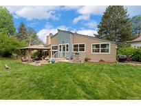 Landscaped backyard with large grassy area, outdoor kitchen and a covered patio with seating area at 6621 E Peakview Pl, Centennial, CO 80111