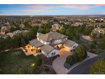 Stunning aerial view of a luxury home with lush landscaping and a circular driveway nestled in a neighborhood near city lights at 6111 Huron Pl, Castle Rock, CO 80108