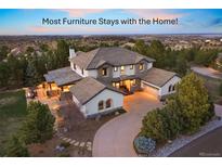 Stunning two-story home featuring a tile roof, well-manicured landscaping, and a charming outdoor living space with warm lighting at 6111 Huron Pl, Castle Rock, CO 80108