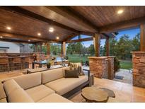 Covered outdoor living space featuring a stone bar, dining, and lounge area with a wood ceiling at 6111 Huron Pl, Castle Rock, CO 80108