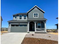 Charming two-story home with a gray exterior, a covered porch, and a two-car garage at 11039 Snowdon St, Parker, CO 80134