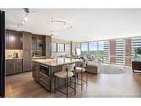 Bright open kitchen with island, breakfast bar, modern lighting, and hardwood floors with adjacent living area and large windows at 3100 E Cherry Creek South Dr # 1403, Denver, CO 80209