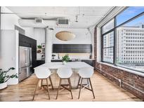 Bright kitchen with modern appliances, island with bar seating, exposed brick, and large windows at 2000 Arapahoe St # 503, Denver, CO 80205