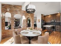Charming dining area with brick arches, modern light fixture, and hardwood floors; a chef's kitchen adjacent at 600 Cascade Dr, Golden, CO 80403