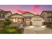 Charming home featuring a well-manicured lawn, inviting porch, and convenient two-car garage with a beautiful sunset at 8814 S Winnipeg Ct, Aurora, CO 80016
