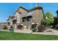 Green townhome exterior with landscaping, walkway, and a bench at 18726 E Yale Cir # F, Aurora, CO 80013