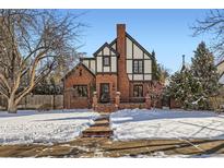 Brick Tudor home with snow-covered lawn and walkway at 1650 Locust St, Denver, CO 80220