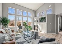 Bright living room featuring large windows, fireplace, tile floors, and modern decor at 11005 Cannonade Dr, Parker, CO 80138
