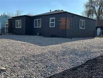 Beautiful exterior view of home with dark siding and gravel landscaping with bright white framed windows at 1285 Roslyn St, Denver, CO 80220