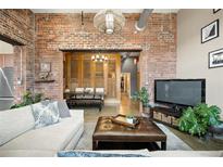 Cozy living room features exposed brick, comfortable seating, and an inviting, open layout to dining space at 2500 Walnut St # 201, Denver, CO 80205