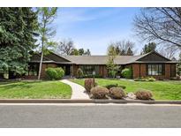 Charming single-story home with lush lawn, mature trees, and inviting walkway leading to the front door at 5290 Nassau E Cir, Cherry Hills Village, CO 80113