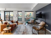 Inviting living room featuring expansive windows showcasing beautiful city views and hardwood floors at 1750 Wewatta St # 830, Denver, CO 80202