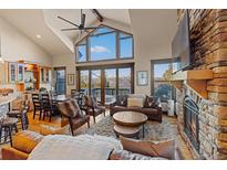 Spacious living room featuring vaulted ceilings, a stone fireplace, and stunning mountain views at 85 Uncle Sam Lode, Breckenridge, CO 80424
