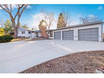 Charming single-Gathering home featuring an attached three-car garage, a brick chimney, and a long concrete driveway at 4145 Dudley St, Wheat Ridge, CO 80033