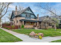 Charming brick two-story home with manicured lawn, mature trees, and inviting front porch at 3701 Eliot St, Denver, CO 80211