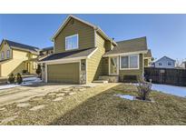 House exterior with green siding, attached garage, and landscaping at 5126 Elkhart St, Denver, CO 80239