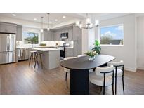 Bright, modern kitchen with gray cabinets, stainless steel appliances, and a center island adjacent to a dining area at 5189 Carr St, Arvada, CO 80002